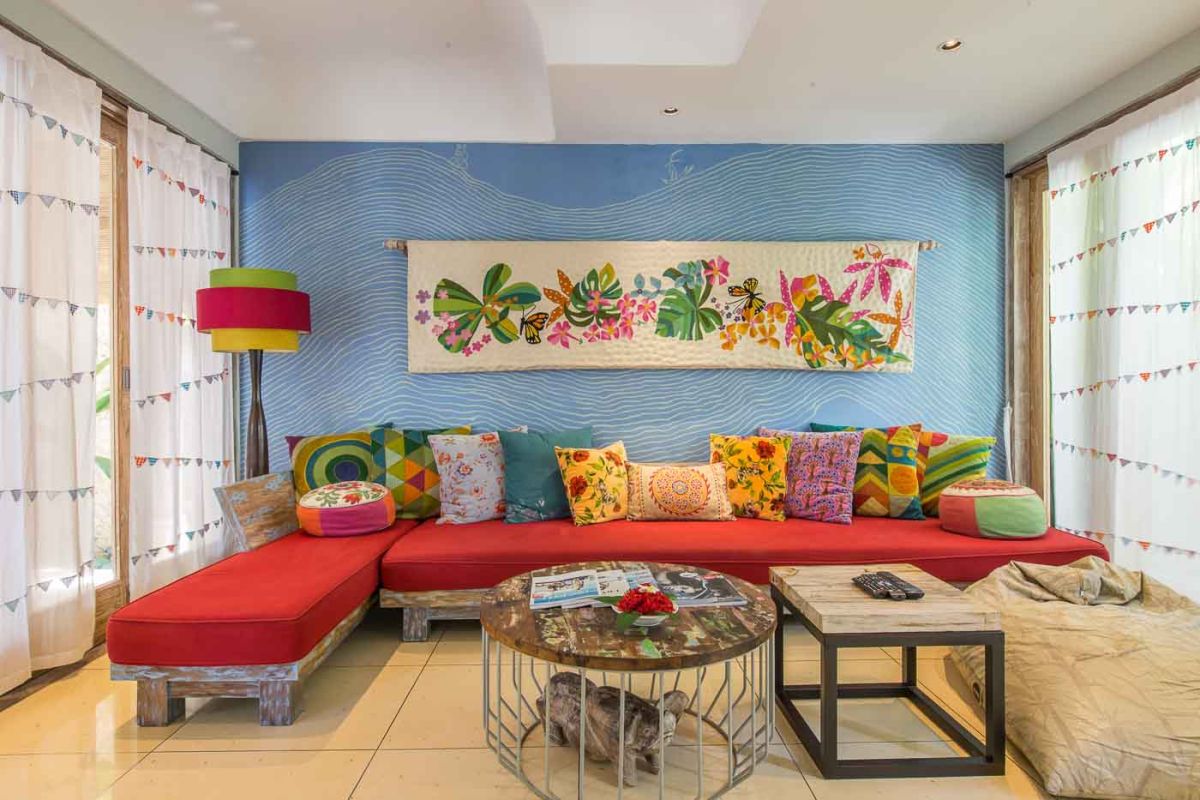 Serene open-air Balinese bathroom featuring a green freestanding bathtub with pink rose petals, tropical plants, and intricate carved wall panels. - Bali Villas