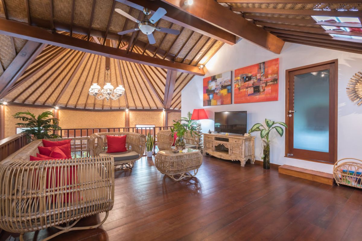 Modern Balinese bathroom with teak wood walls, pebble stone floor, rustic black stone sink, snake plants, and woven accents. - Bali Villas