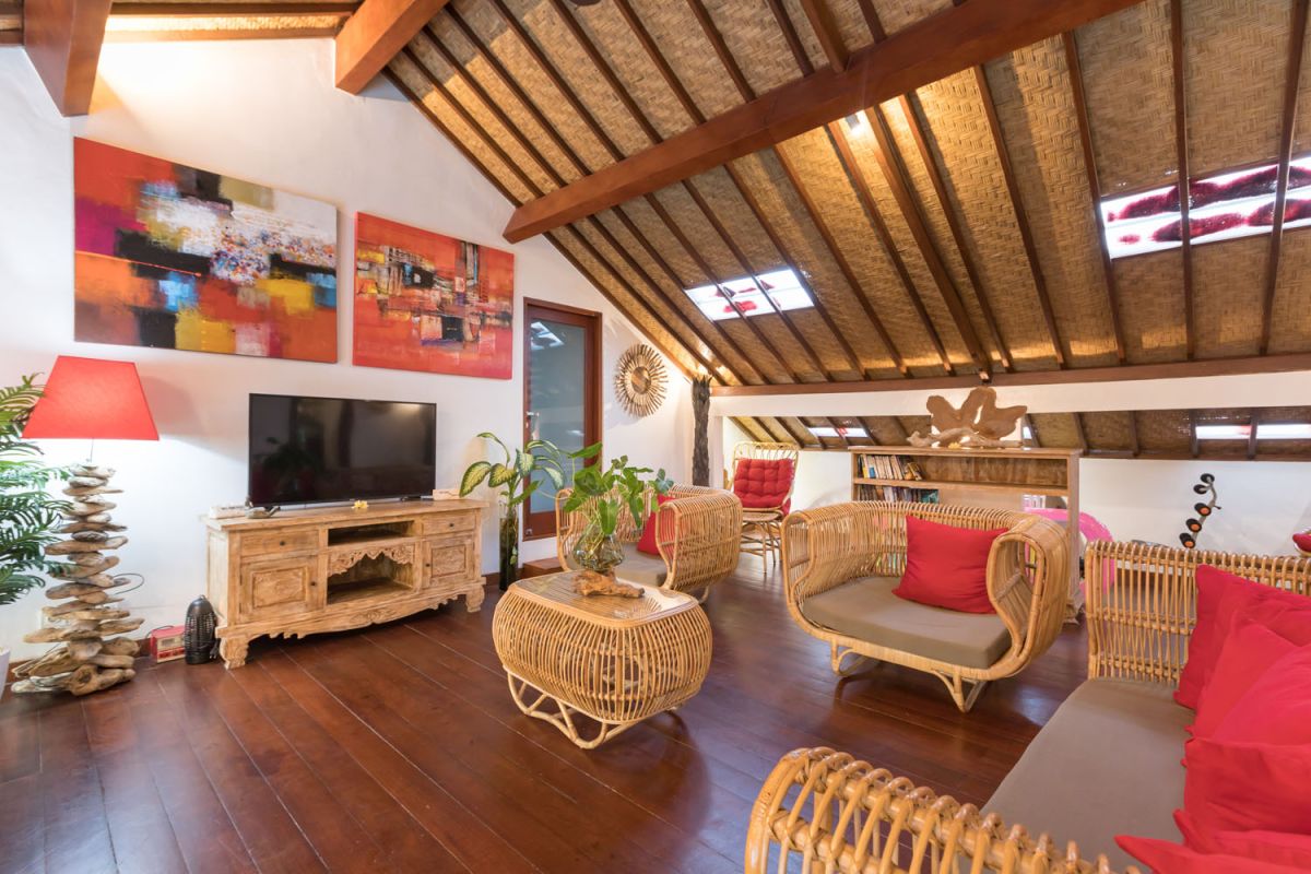 Modern Balinese bathroom with teak wood walls, pebble stone floor, rustic black stone sink, snake plants, and woven accents. - Bali Villas