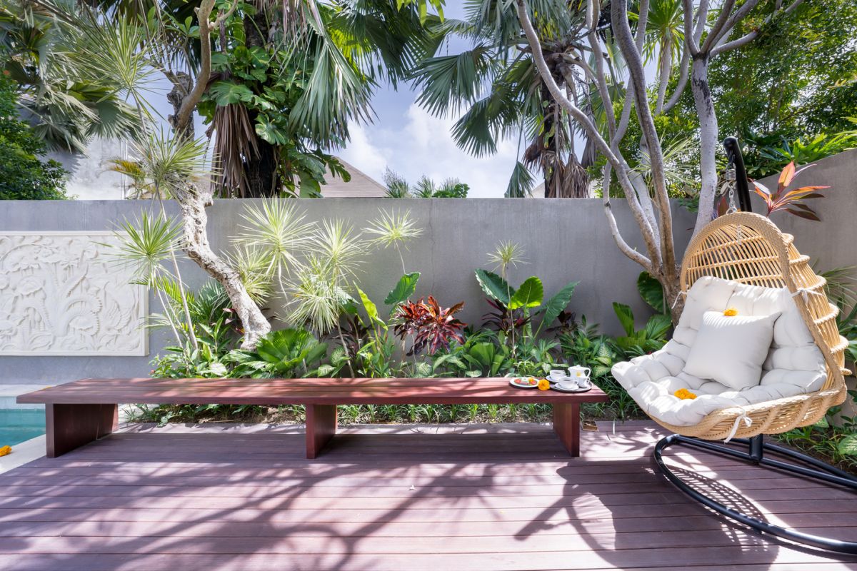 Modern luxury bathroom with soaking tub filled with water and lotus flowers, glass shower enclosure, tropical plants, and natural stone vanity. - Bali Villas
