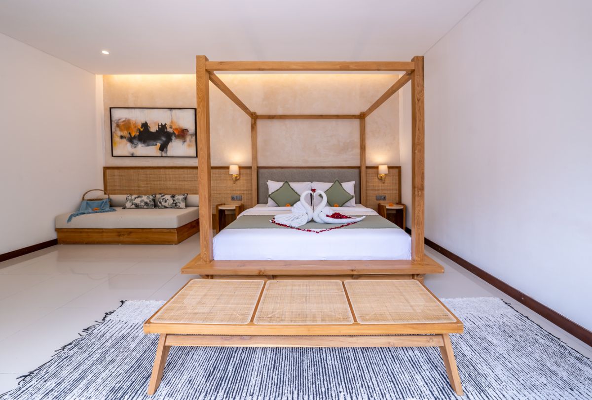 Modern luxury bathroom with soaking tub filled with water and lotus flowers, glass shower enclosure, tropical plants, and natural stone vanity. - Bali Villas