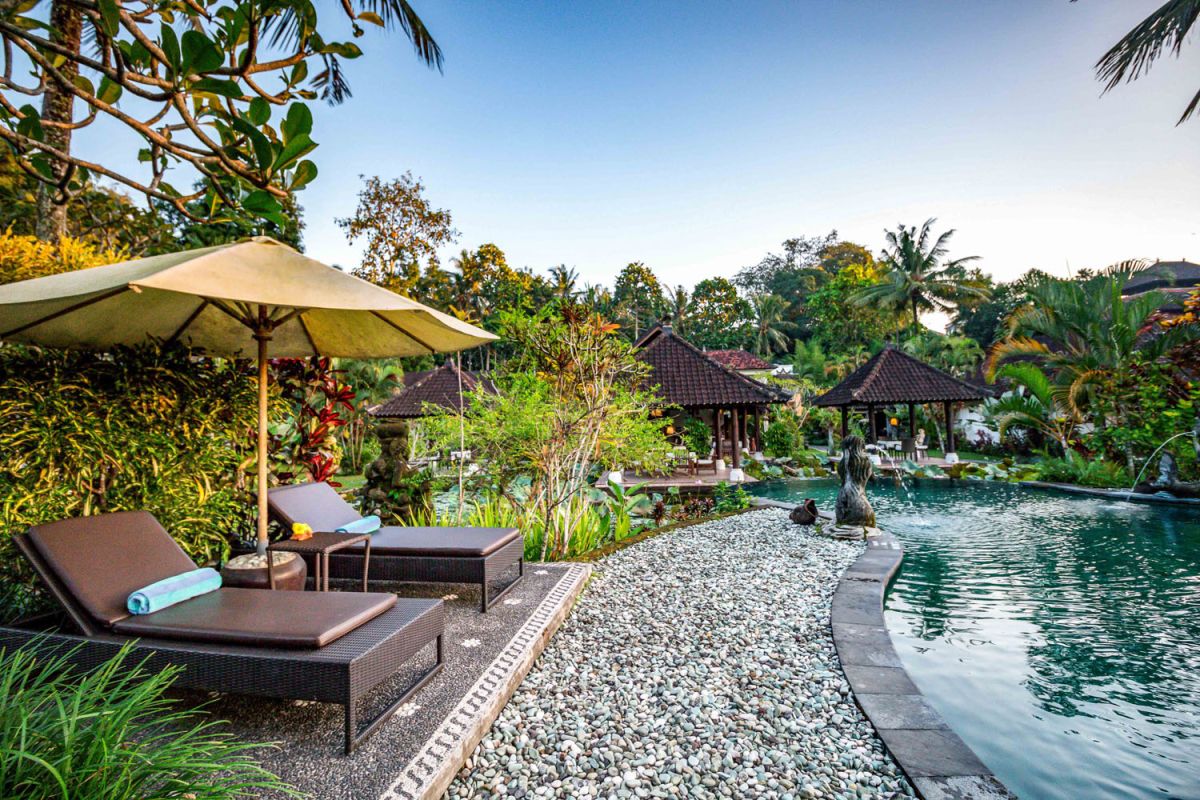 Spacious open-air Balinese pavilion restaurant with thatched roof, wooden tables set for dining, and lush tropical greenery. - Bali Villas