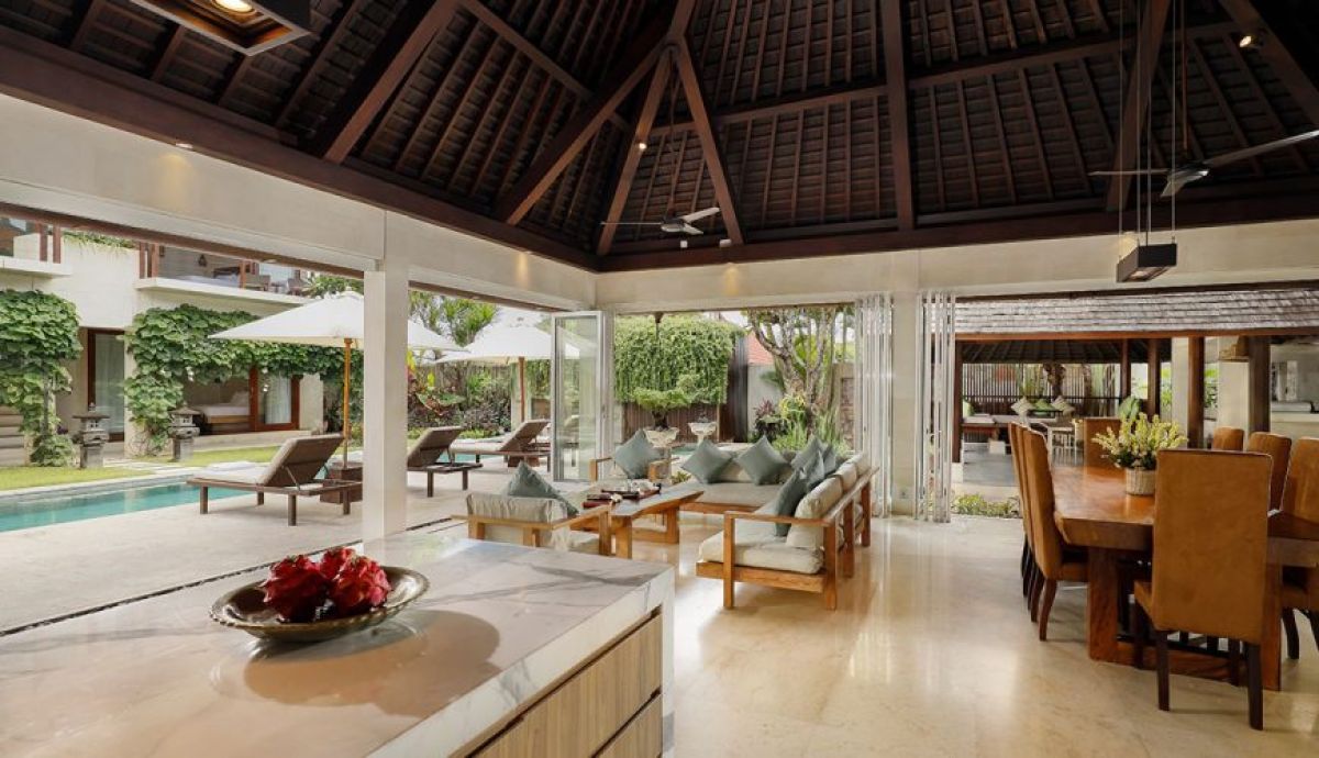 Luxurious Balinese bathroom with flower-petaled freestanding tub, tropical plants, stone walls, and open shower. - Bali Villas