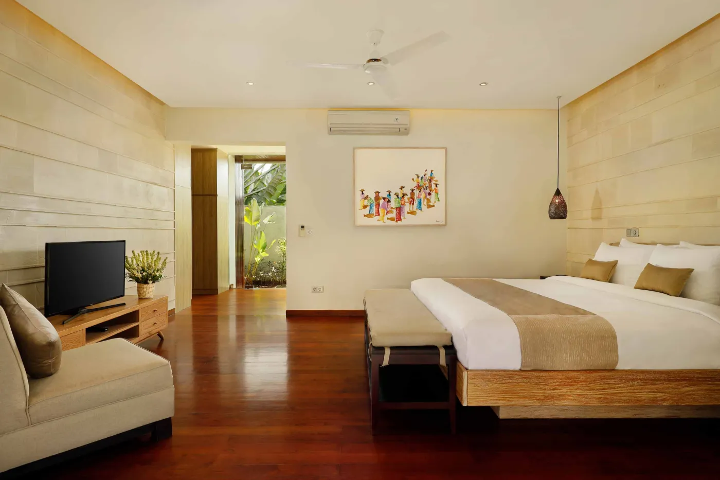 Luxurious Balinese-style bathroom featuring a petal-filled freestanding bathtub, glass shower, wooden vanity, and lush tropical plants. - Bali Villas