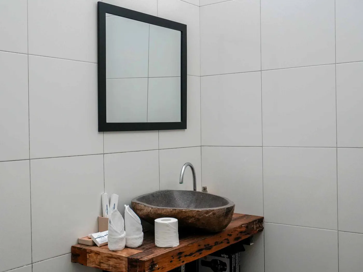 Modern bathroom with glass shower enclosure, rain showerhead, and wooden vanity sink. - Bali Villas