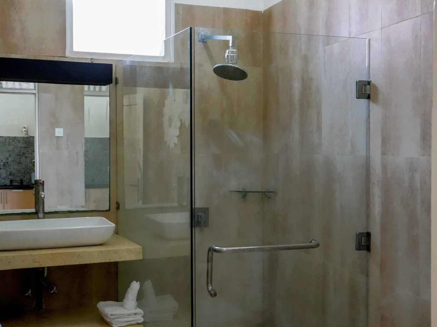 Modern bathroom with glass shower enclosure, rain showerhead, and wooden vanity sink. - Bali Villas