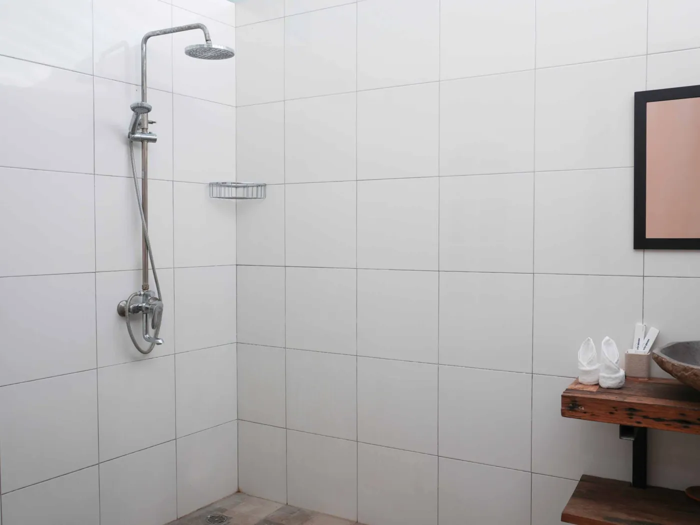 Modern bathroom with glass shower enclosure, rain showerhead, and wooden vanity sink. - Bali Villas