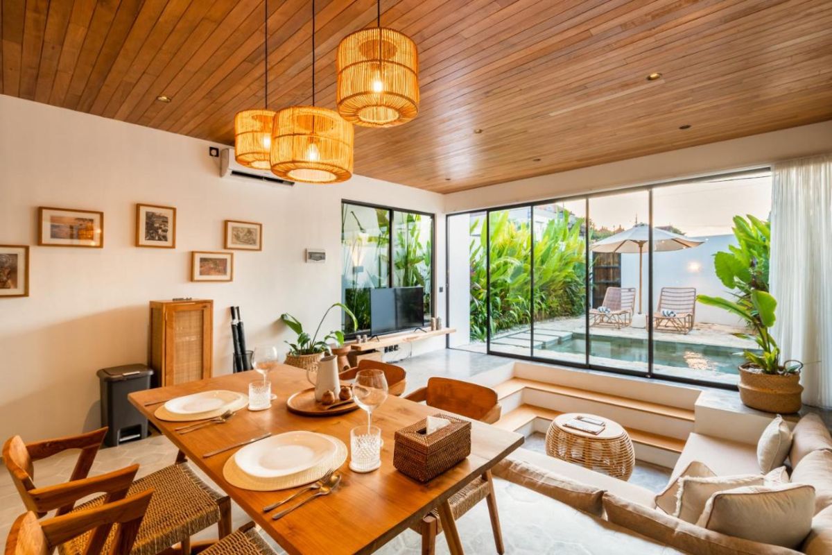 Serene modern bedroom with wooden bed, desk, and large windows overlooking lush green rice fields. - Bali Villas