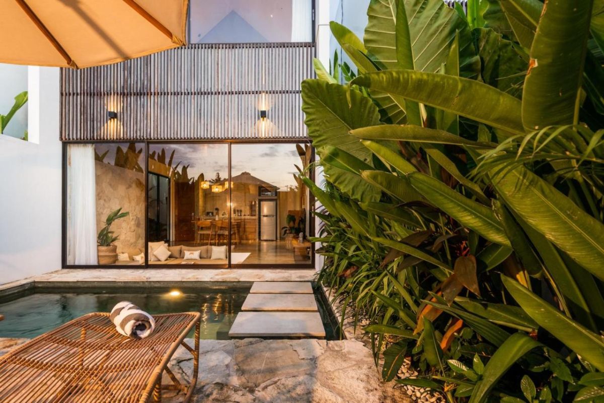 Serene modern bedroom with wooden bed, desk, and large windows overlooking lush green rice fields. - Bali Villas