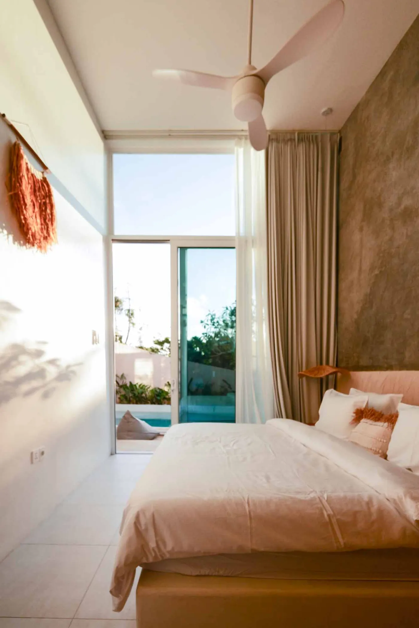 Serene bohemian bathroom with white bathtub, wooden vanity, rattan mirror, potted palm, and woven accents. - Bali Villas