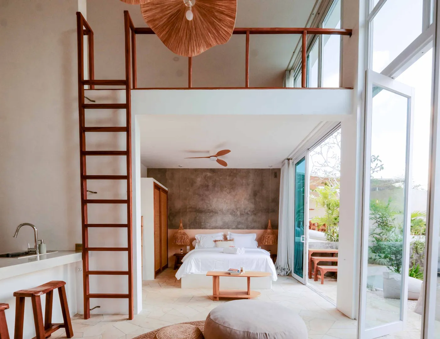 Serene bohemian bathroom with white bathtub, wooden vanity, rattan mirror, potted palm, and woven accents. - Bali Villas