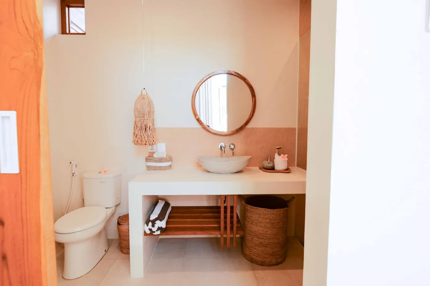 Serene bohemian bathroom with white bathtub, wooden vanity, rattan mirror, potted palm, and woven accents. - Bali Villas