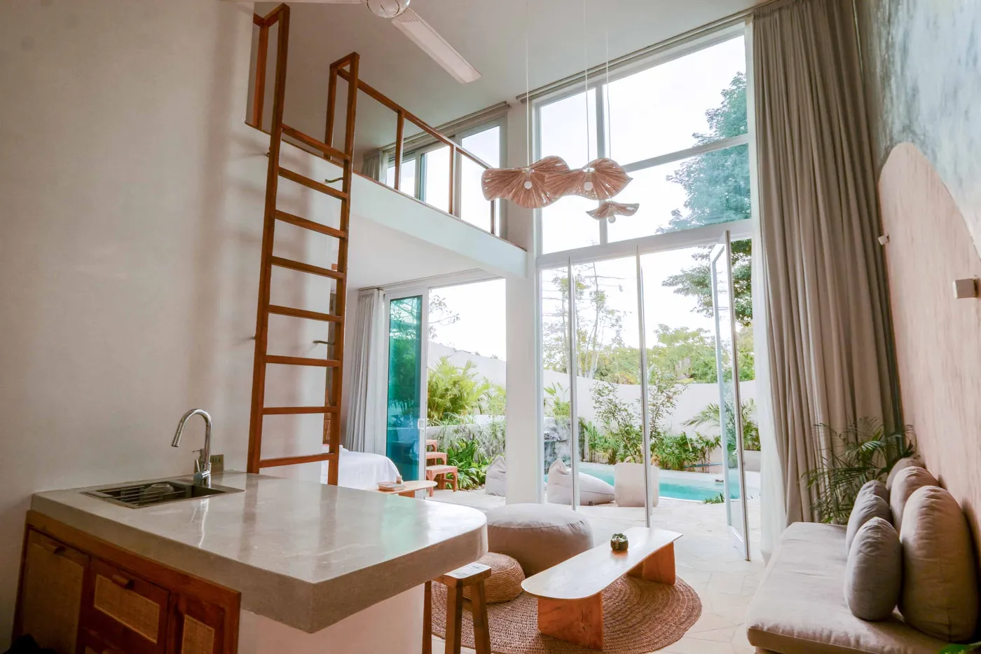Serene bohemian bathroom with white bathtub, wooden vanity, rattan mirror, potted palm, and woven accents. - Bali Villas