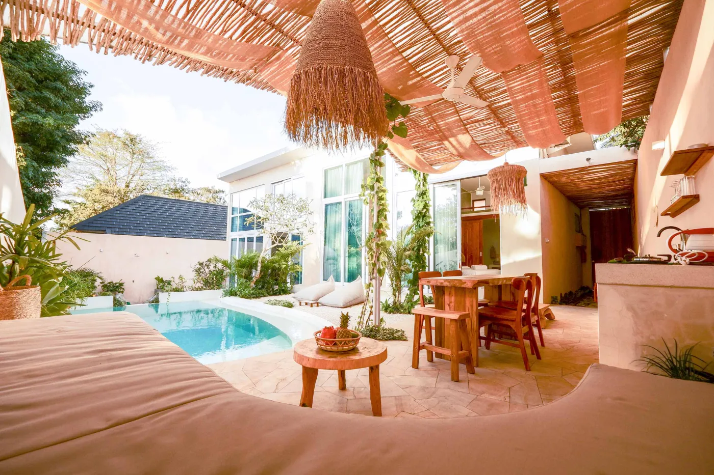 Serene bohemian bathroom with white bathtub, wooden vanity, rattan mirror, potted palm, and woven accents. - Bali Villas