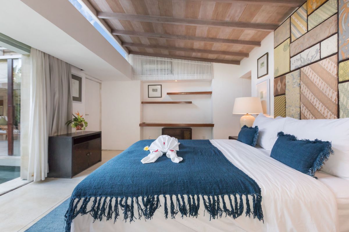 Spacious modern tropical villa interior with wooden furniture, lush plants, and open views to a pool. - Bali Villas