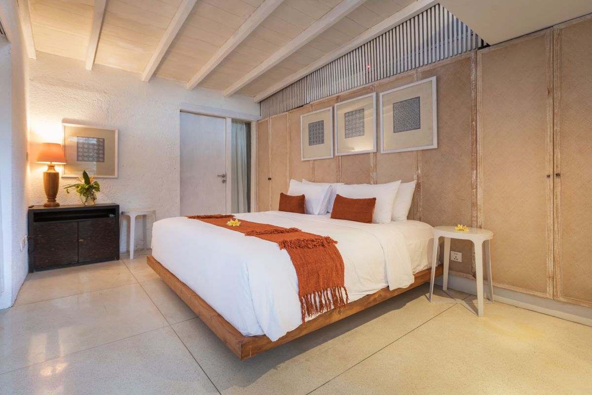 Spacious modern tropical villa interior with wooden furniture, lush plants, and open views to a pool. - Bali Villas