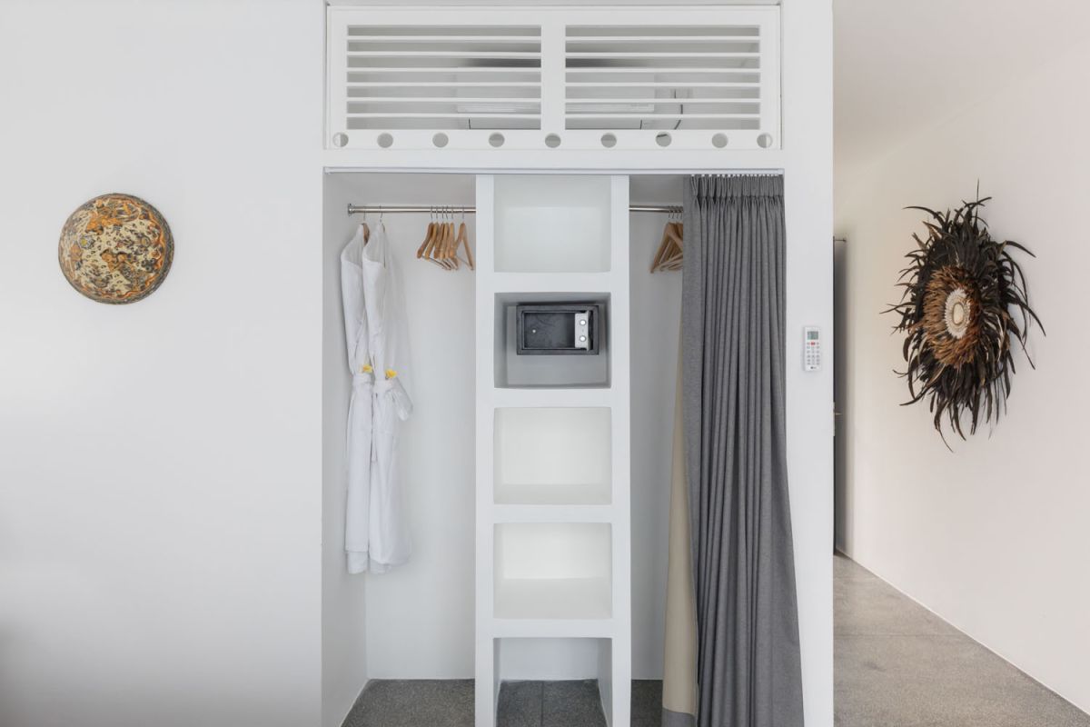 Spacious modern Bali villa interior featuring a purple modular sofa, abstract African-inspired wall art, wooden dining table, and polished concrete floors. - Bali Villas