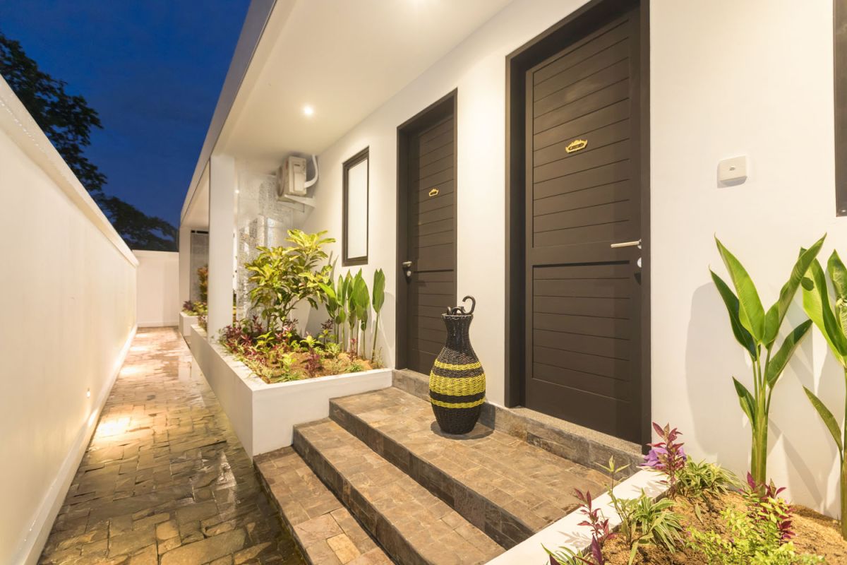 Spacious modern Bali villa interior featuring a purple modular sofa, abstract African-inspired wall art, wooden dining table, and polished concrete floors. - Bali Villas
