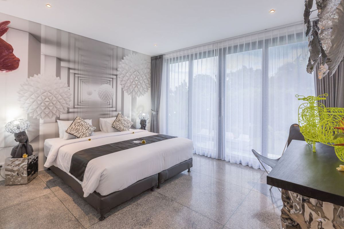 Spacious modern Bali villa interior featuring a purple modular sofa, abstract African-inspired wall art, wooden dining table, and polished concrete floors. - Bali Villas