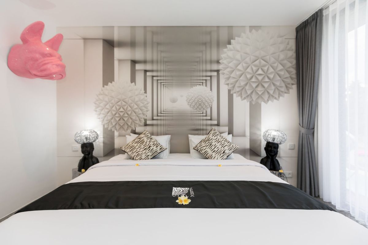 Spacious modern Bali villa interior featuring a purple modular sofa, abstract African-inspired wall art, wooden dining table, and polished concrete floors. - Bali Villas