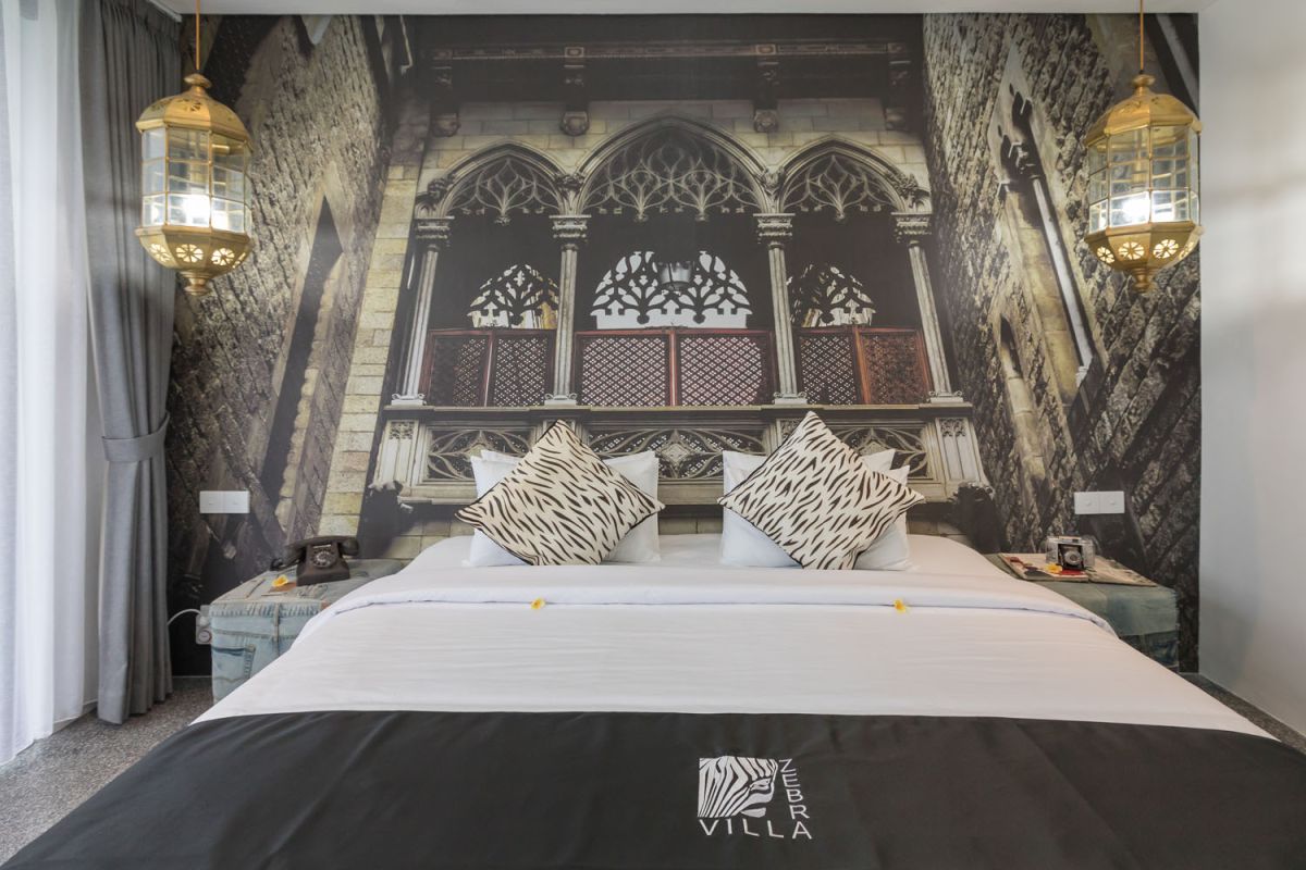 Spacious modern Bali villa interior featuring a purple modular sofa, abstract African-inspired wall art, wooden dining table, and polished concrete floors. - Bali Villas