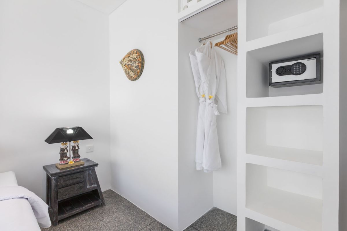 Spacious modern Bali villa interior featuring a purple modular sofa, abstract African-inspired wall art, wooden dining table, and polished concrete floors. - Bali Villas