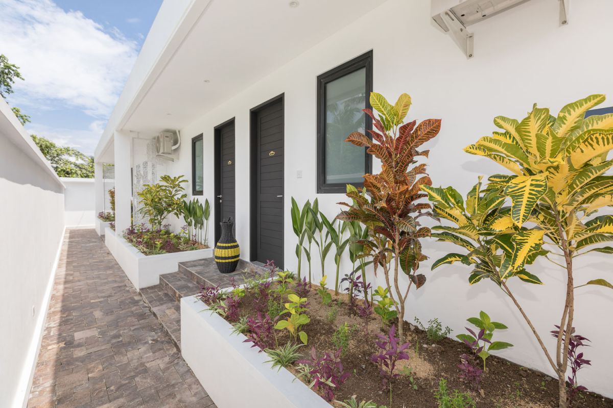 Spacious modern Bali villa interior featuring a purple modular sofa, abstract African-inspired wall art, wooden dining table, and polished concrete floors. - Bali Villas