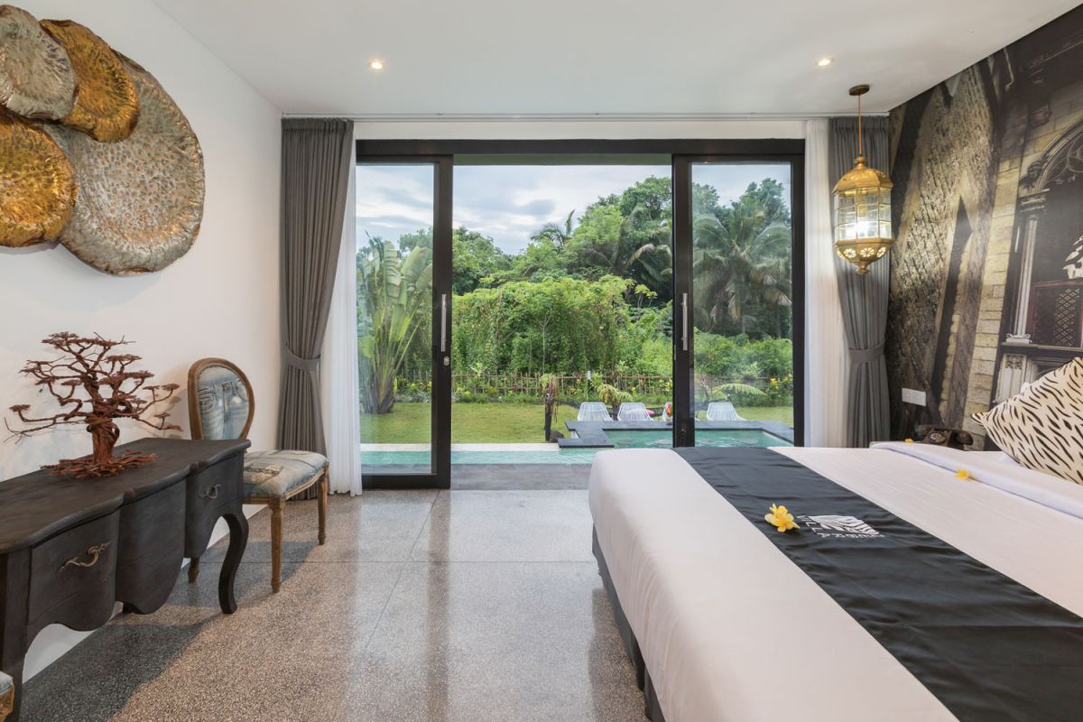 Spacious modern Bali villa interior featuring a purple modular sofa, abstract African-inspired wall art, wooden dining table, and polished concrete floors. - Bali Villas