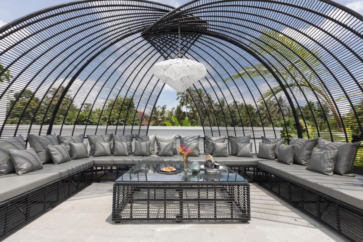 Spacious modern Bali villa interior featuring a purple modular sofa, abstract African-inspired wall art, wooden dining table, and polished concrete floors. - Bali Villas