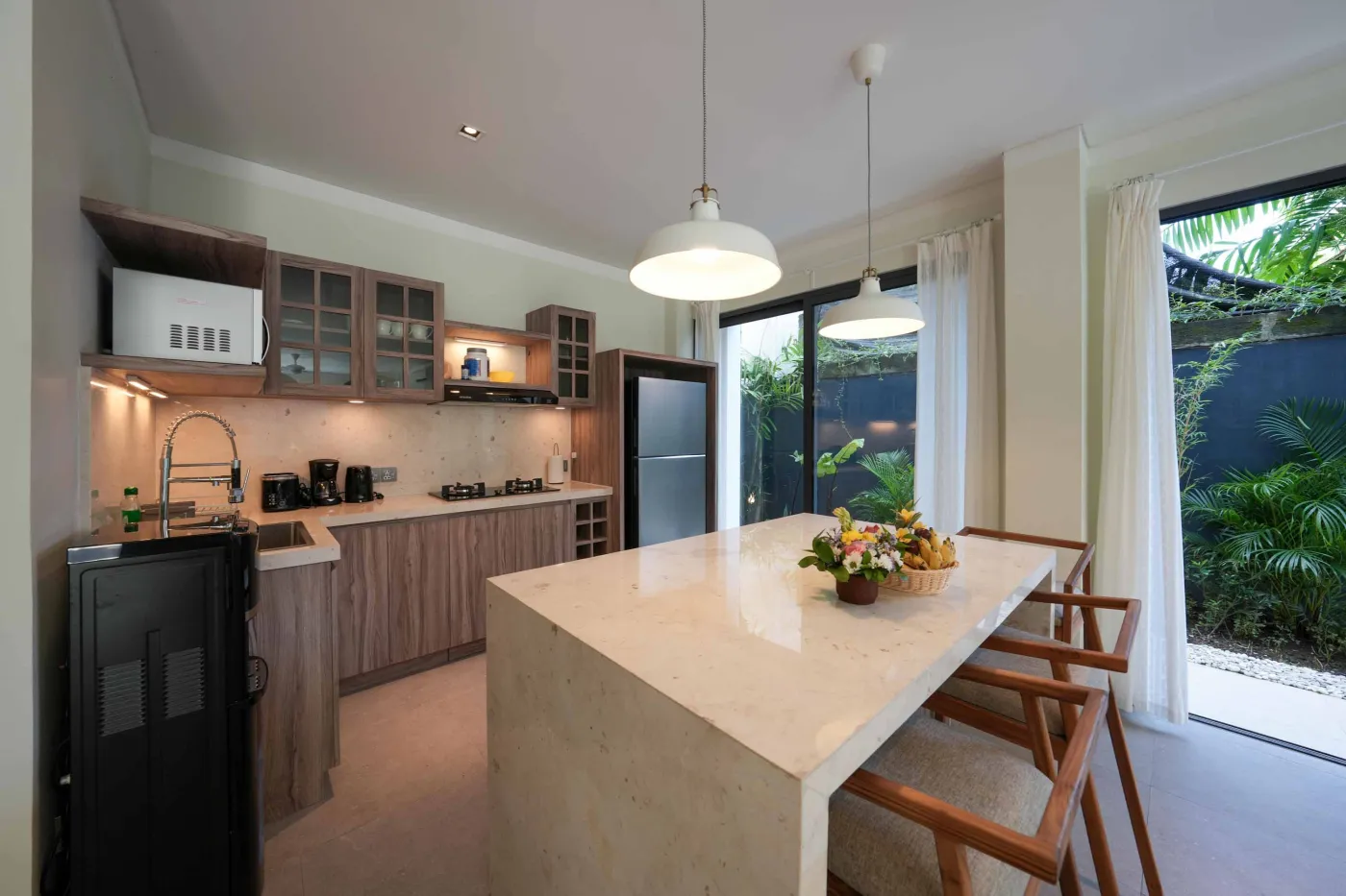 White freestanding bathtub filled with water and floating red rose petals in a modern spa-like bathroom. - Bali Villas
