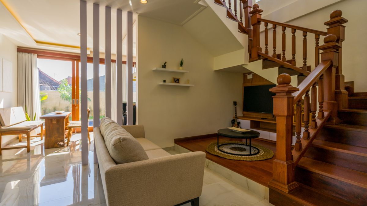 Serene Bali villa poolside patio with wooden dining set under blue umbrella, surrounded by tropical plants and traditional architecture. - Bali Villas