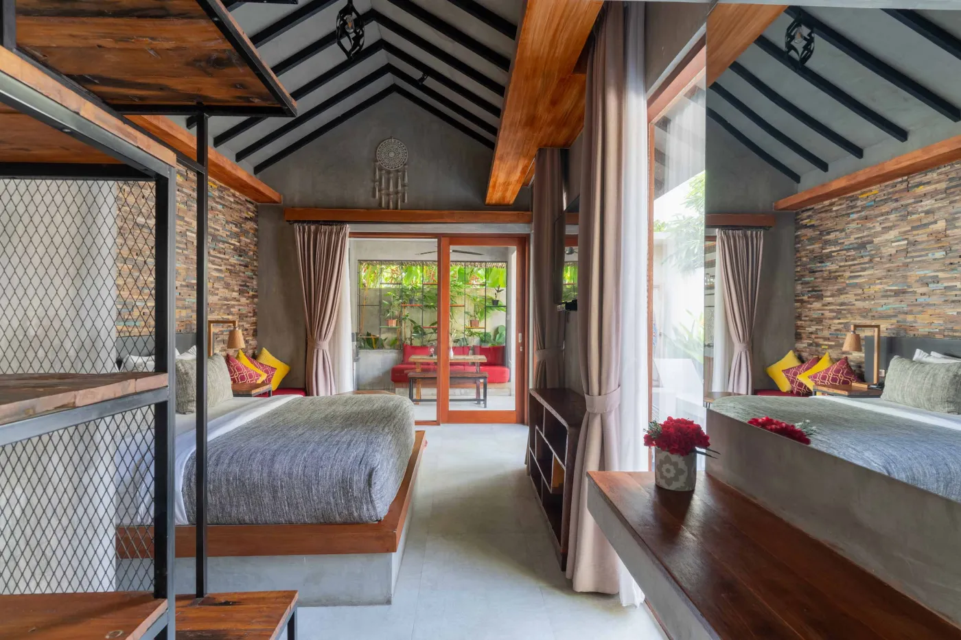 Rustic tropical kitchen with wooden cabinets, shelves of jars, tiled sink, and lush green plant wall behind metal frame, plus wooden dining bench and table. - Bali Villas