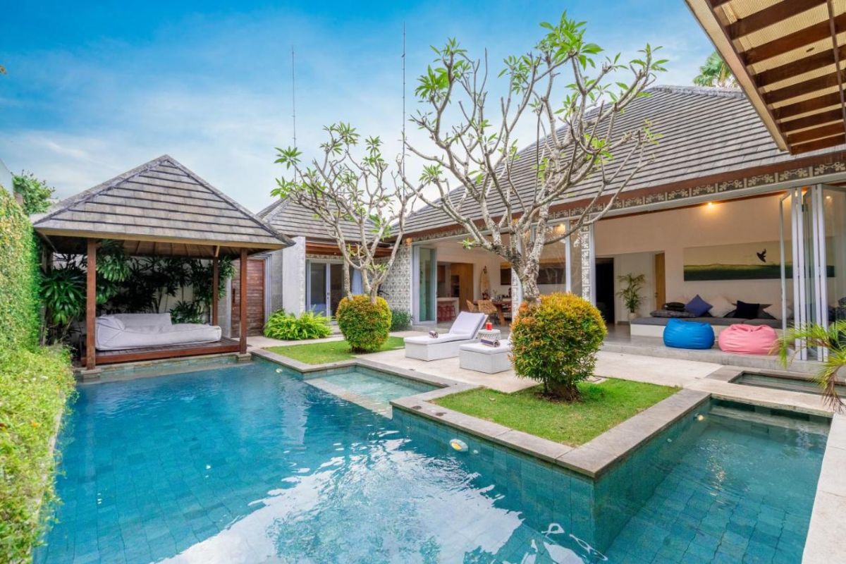 Luxurious Balinese villa featuring an infinity pool, outdoor lounge with daybeds, and lush tropical garden. - Bali Villas