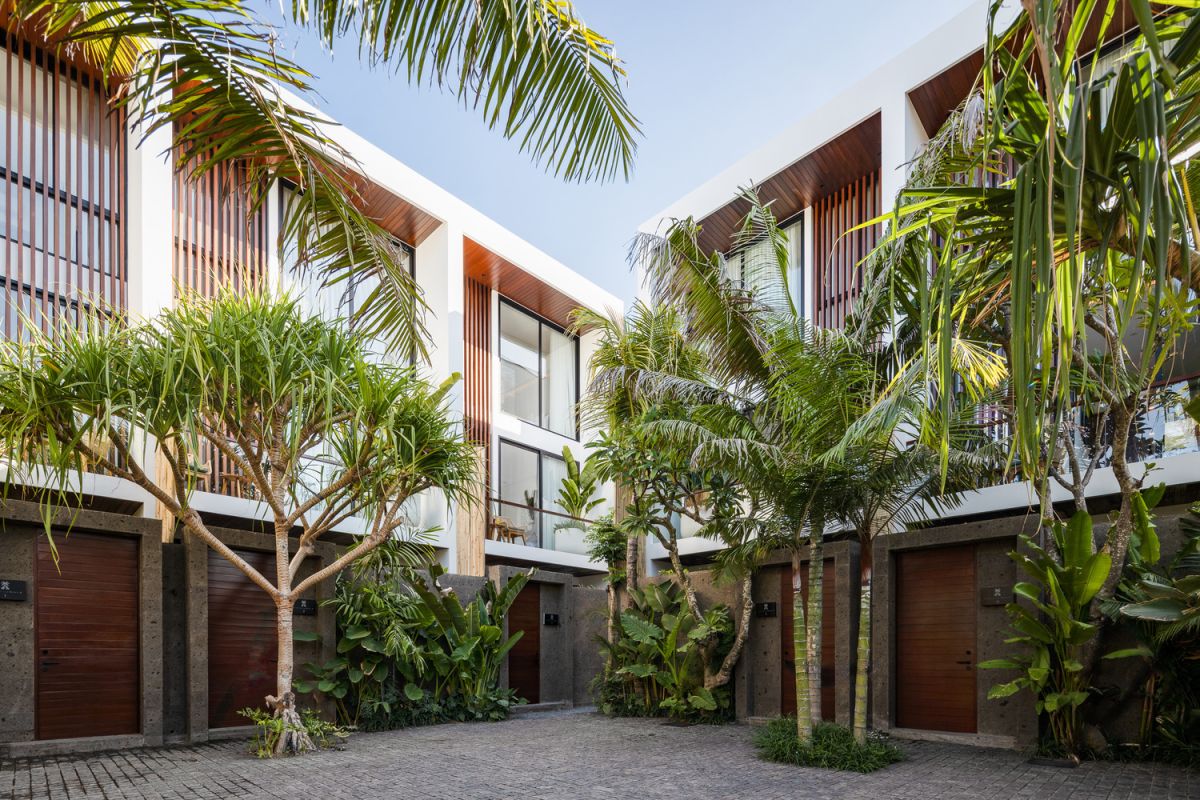 Modern tropical villa courtyard with white walls, wooden shutters, and lush palm trees. - Bali Villas