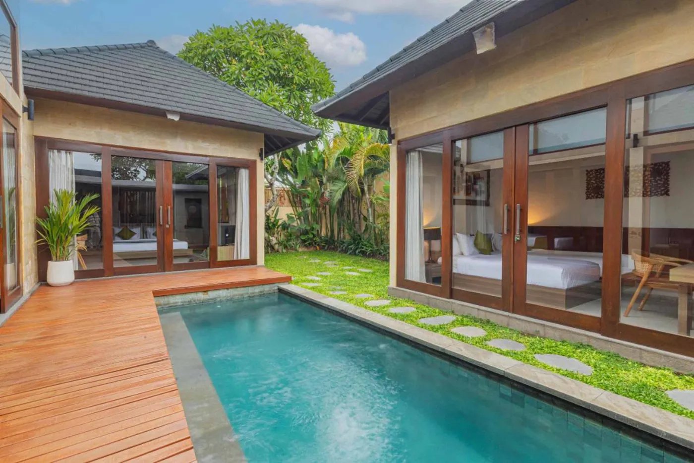 Luxurious Balinese villa with turquoise lap pool, wooden deck, tropical garden, and open bedroom suite. - Bali Villas