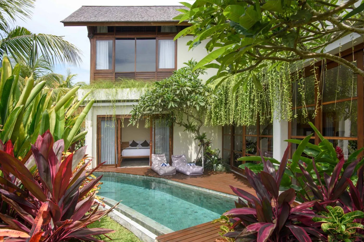 Luxurious tropical villa with private infinity pool, lush greenery, and wooden decking in Bali. - Bali Villas