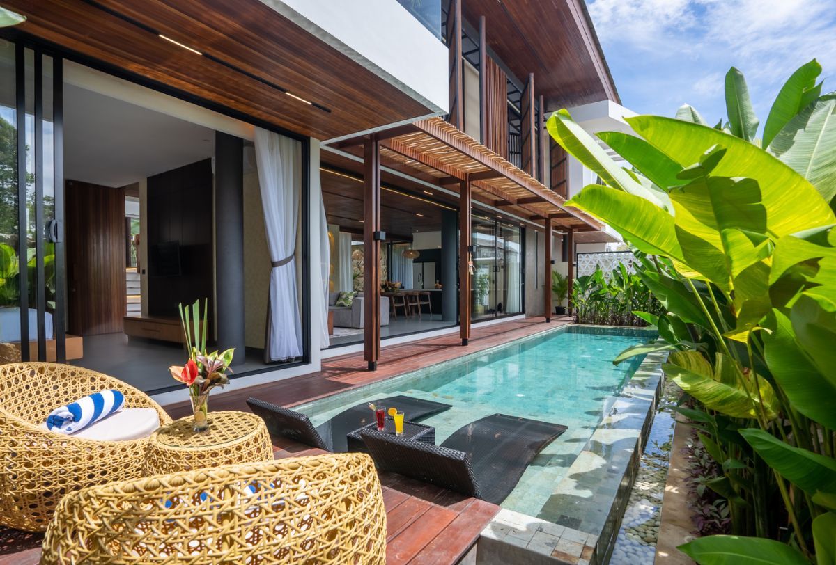 Modern tropical luxury villa with infinity pool, rattan lounge chairs, tropical drinks, and lush banana leaves. - Bali Villas