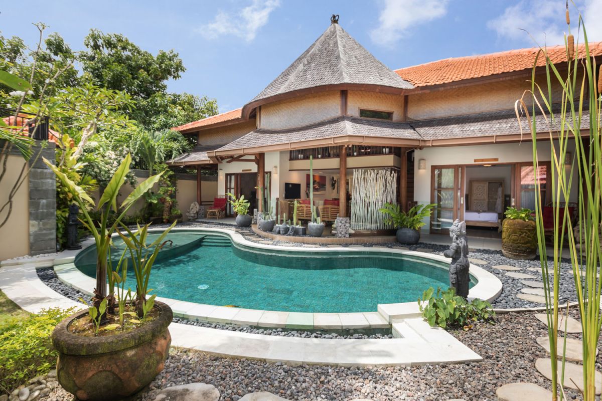 Luxurious Balinese villa with curved turquoise pool, tropical gardens, and traditional architecture. - Bali Villas