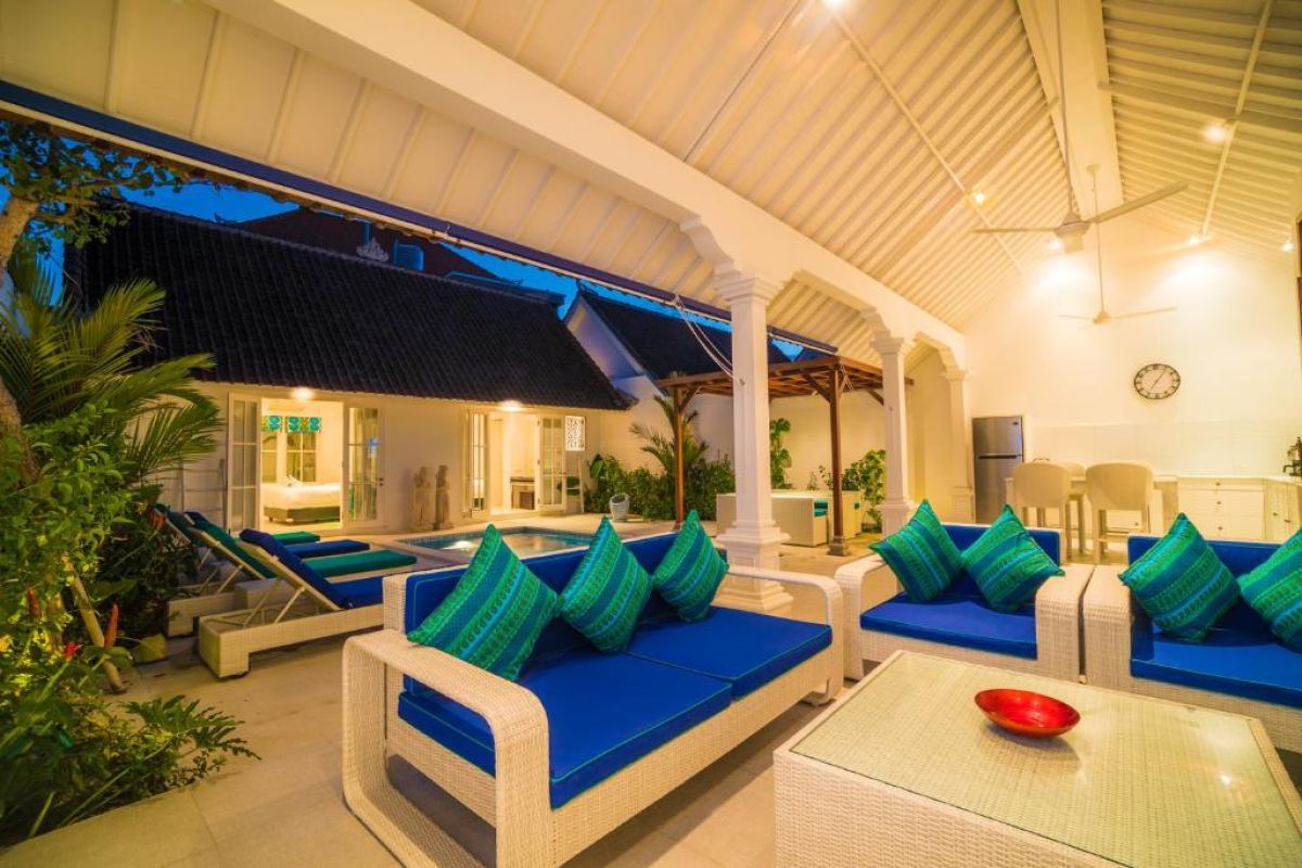 Modern gray-tiled bathroom featuring a white sink vanity, mirror, toilet, potted plants, and decorative window. - Bali Villas