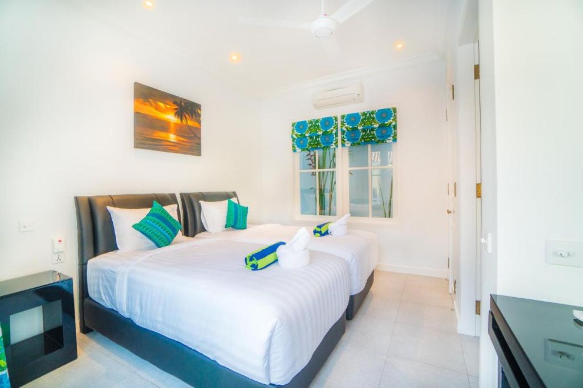 Modern gray-tiled bathroom featuring a white sink vanity, mirror, toilet, potted plants, and decorative window. - Bali Villas
