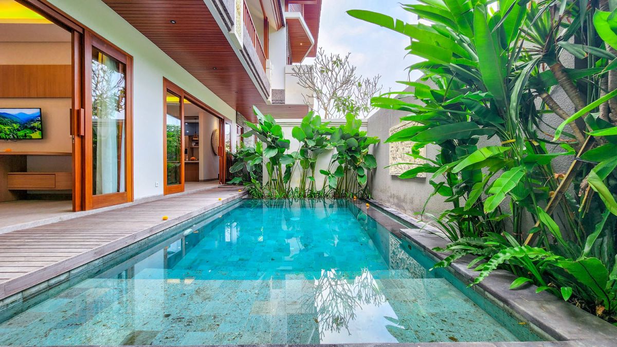 Modern Bali villa with private infinity pool, lush tropical plants, and wooden deck. - Bali Villas