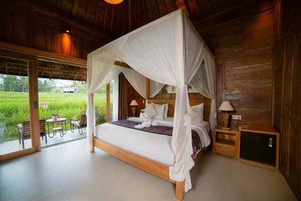 Luxurious Balinese bedroom with white canopy four-poster bed overlooking lush rice terraces.
