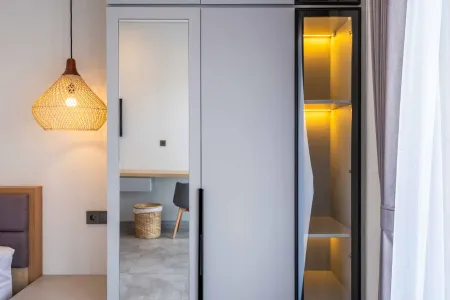 Modern bedroom wardrobe with sliding mirrored door, yellow LED-lit glass panel, rattan pendant lamp, and neutral decor.