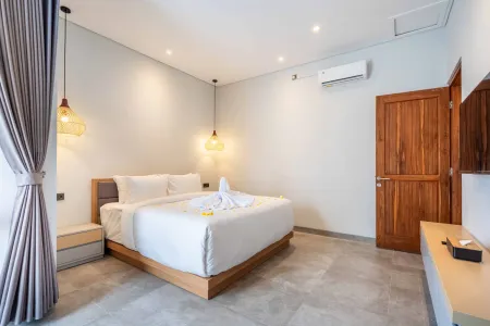 Serene Bali villa bedroom with king bed, white linens, swan towel art adorned with frangipani flowers, wooden accents, and soft pendant lighting.
