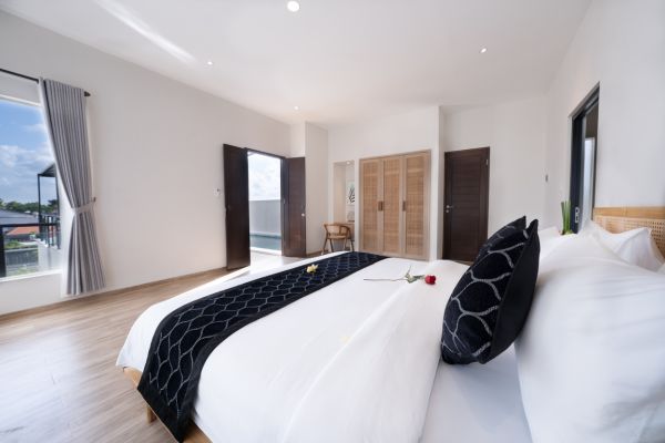 Luxurious tropical bedroom with king-size bed, black patterned runner, balcony doors open to garden view.