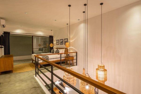 Modern loft bedroom with wooden bed, rattan pendant lights, beige walls, and sliding glass doors to outdoor view.