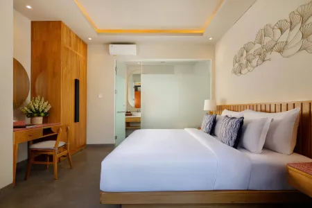 Spacious modern Balinese bedroom with wooden king bed, vanity desk, and frosted glass en-suite bathroom.