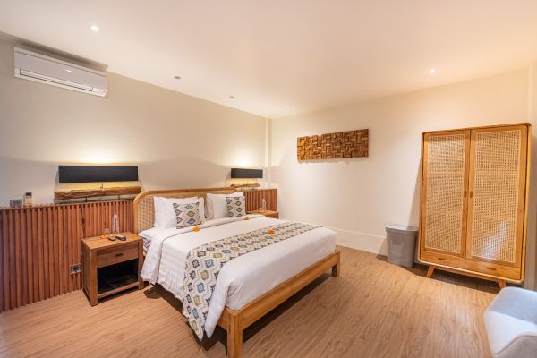Cozy Balinese bedroom interior with wooden king bed, bamboo wardrobe, and soft ambient lighting. - Bali Villas