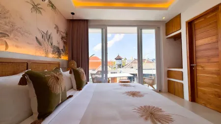 Spacious Balinese bedroom with tropical leaf wallpaper, king bed, and balcony view of traditional temple rooftops.