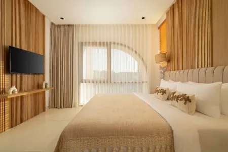 Luxurious modern bedroom with wooden slat walls, king bed in beige linens, arched windows with sheer curtains, and wall-mounted TV.
